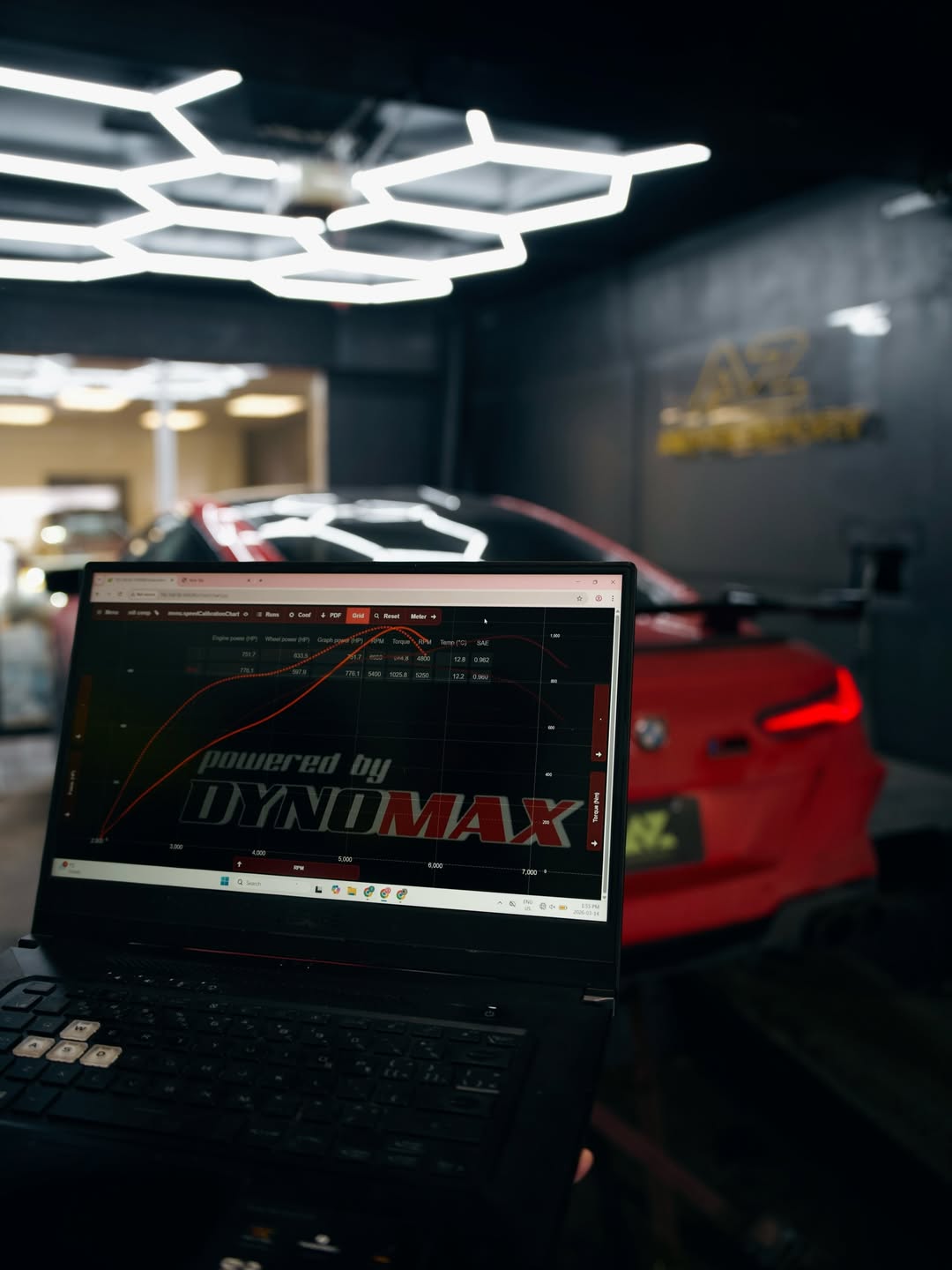 Dynomax pull chart on a laptop with the tuned red BMW M8 behind
